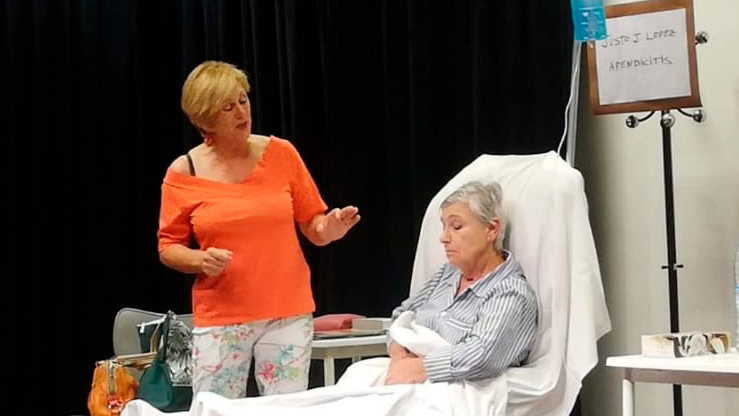 Una mujer en una camilla y otra mujer hablando con ella