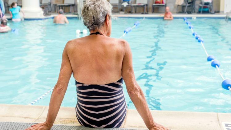 Una mujer sentada en el borde de una piscina